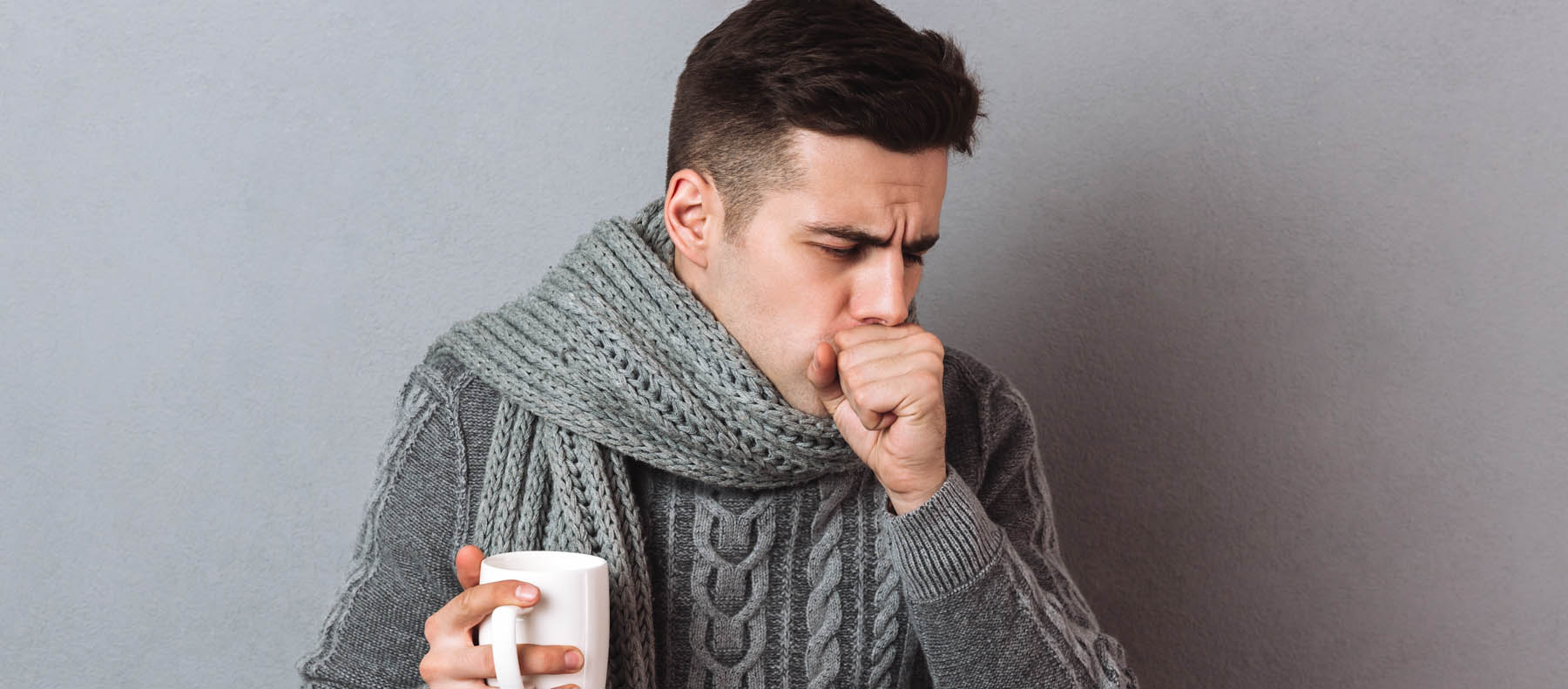 Sick woman sitting in bed, blowing nose with napkin
